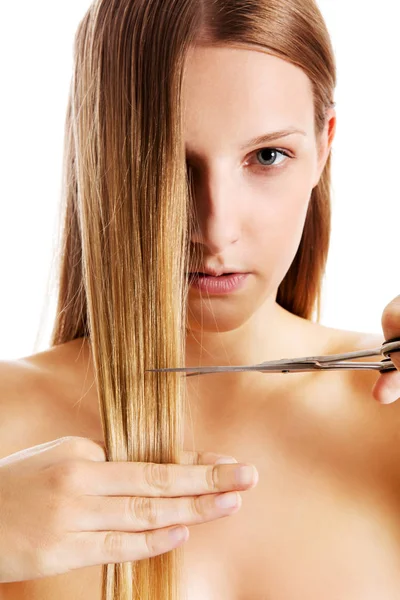 Unga blonda kvinnan klippa hennes hår med sax. — Stockfoto