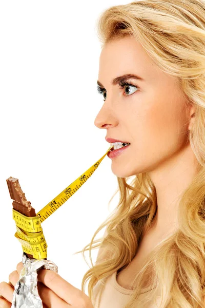 Fiatal nő kezében csokoládé és étkezési intézkedés szalag — Stock Fotó