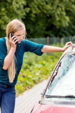 Woman dialing her phone after car crash clipart