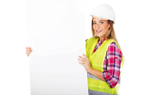 Joven constructora sonriente sosteniendo pancarta vacía — Foto de Stock