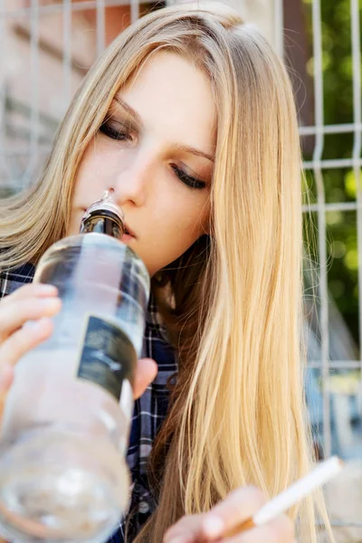 Dronken jonge vrouw met fles alcohol — Stockfoto