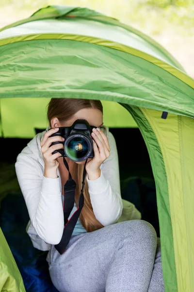 Молодая женщина с фотокамерой в палатке на природе — стоковое фото