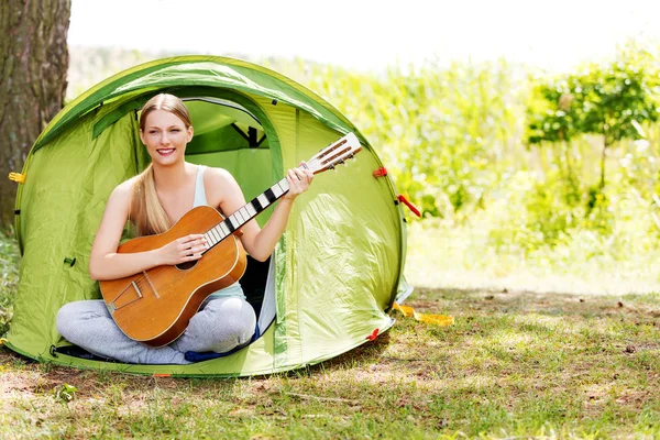 Jonge vrouw speelt gitaar in een tent op de natuur — Stockfoto