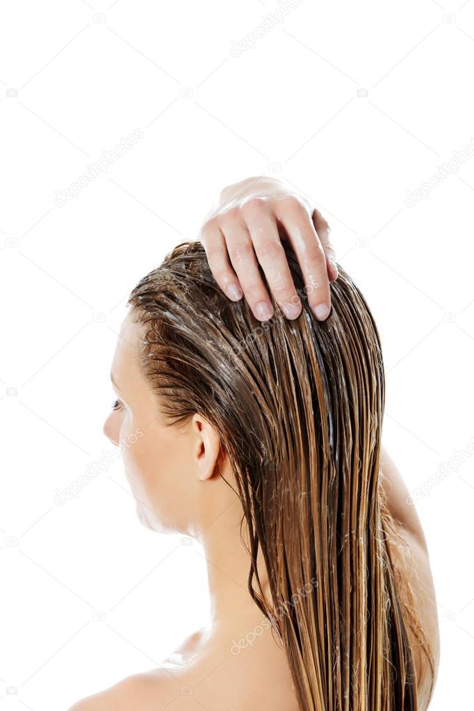 Photo of woman applying hair conditioner.