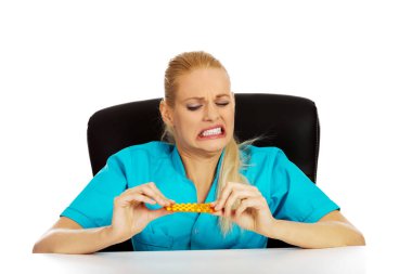 Şok ve korkmuş kadın hemşire ya da doktor arkasında oturan Resepsiyon ve paket hap holding