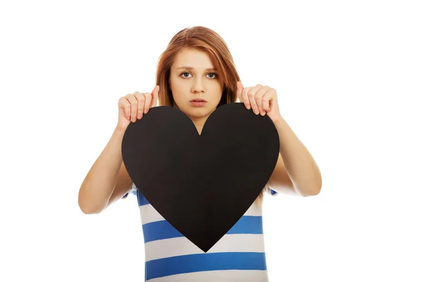 Worried teenage woman holding black paper heart — Stock Photo, Image