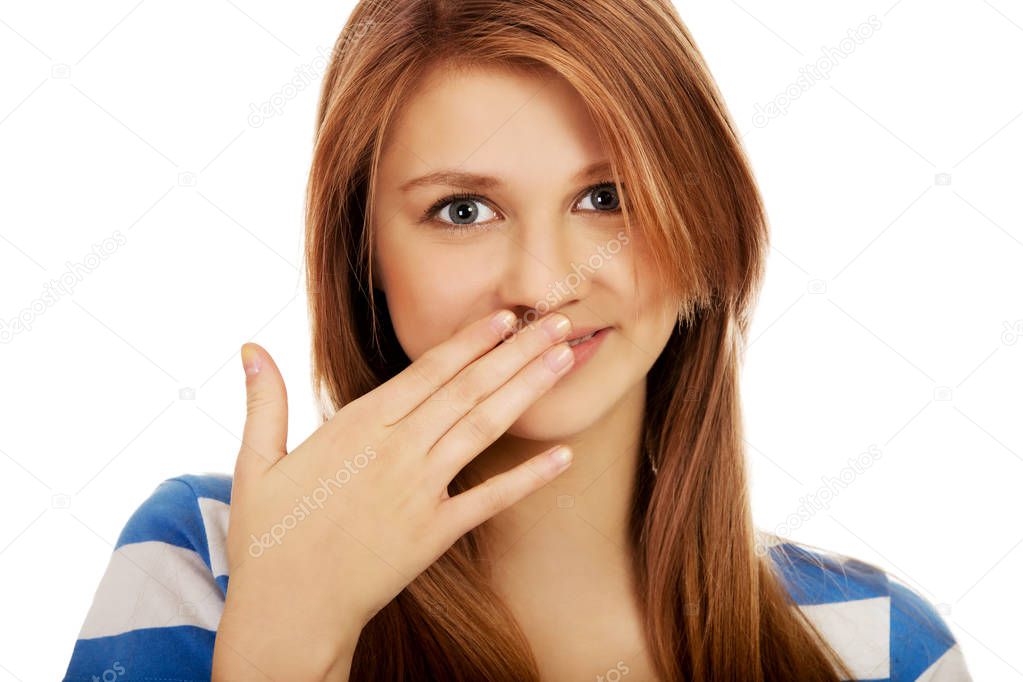 Teenage woman giggles covering her mouth with hand