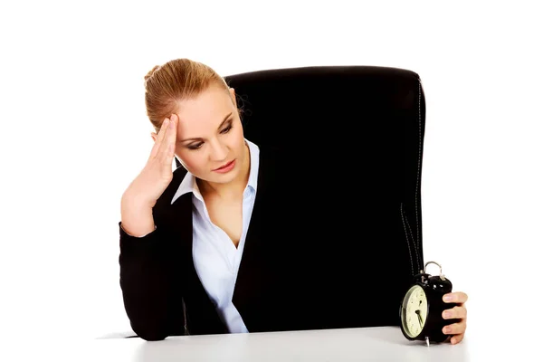 目覚まし時計付きのデスクの後ろに疲れたビジネス女性 — ストック写真