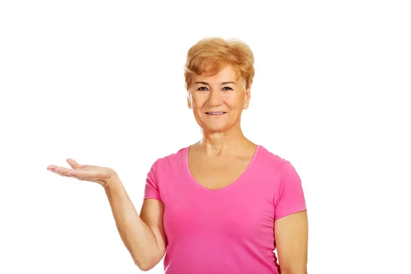 En gammal leende kvinna presentera något — Stockfoto