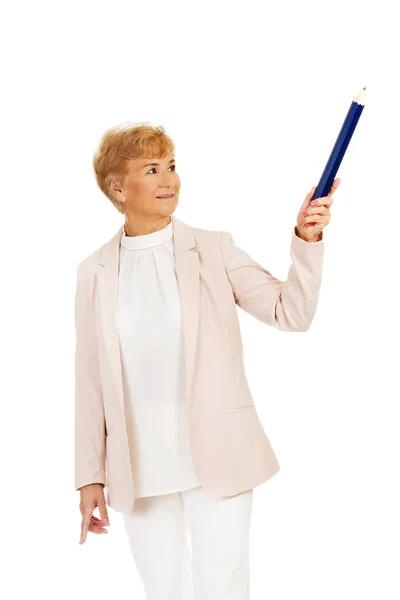 Leende äldre kvinna pekar uppåt med hege penna — Stockfoto