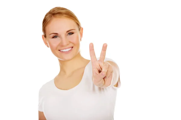 Uśmiechnięta młoda kobieta Wyświetlono znak zwycięstwo — Zdjęcie stockowe