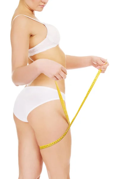 Mladá štíhlá žena měření její stehno žlutou páskou — Stock fotografie