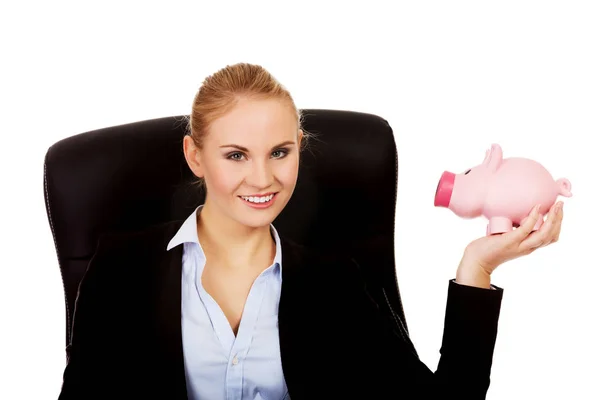 Business woman sitting on armchair and holding piggybank — Stock Photo, Image