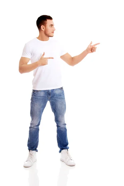 Happy young man pointing at copyspace or something — Stock Photo, Image