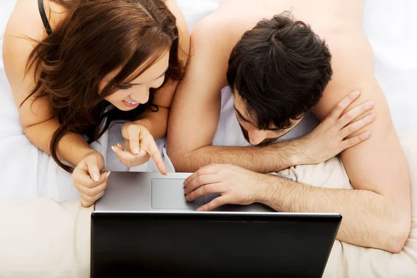 Szczęśliwa para na komputerze przenośnym w sypialni. — Zdjęcie stockowe
