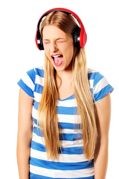 Giovane donna con cuffie che ascolta e canta musica, isolata su bianco — Foto Stock