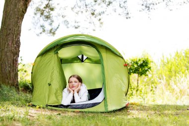 Doğada bir çadırda dinlenen genç kadın.