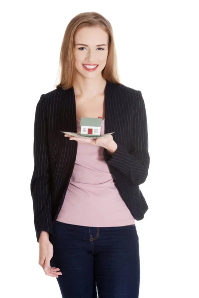 Beautiful casual caucasian business woman holding house model on her palm. — Stock Photo, Image