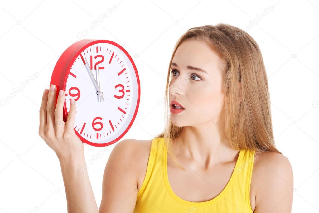 Beautiful caucasian casual woman holding red clock.
