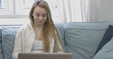 Kanepede dizüstü bilgisayar kullanan kadın