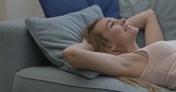 Woman laying on couch smiling and looking at camera — Stock Video