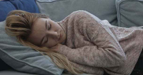 Молода сонна жінка падає на диван вдома . — стокове відео