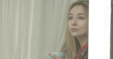 Güzel genç bayan kahve içiyor ve pencereden bakıyor..