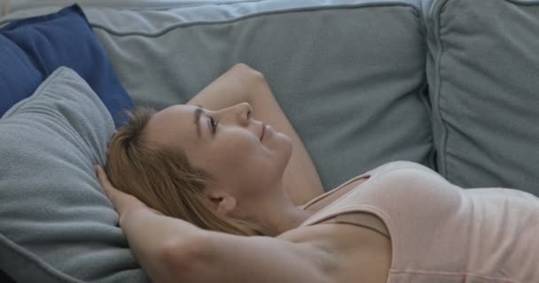 Žena ležící na gauči s úsměvem a při pohledu na fotoaparát — Stock video