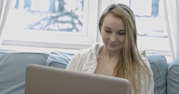 Жінка використовує ноутбук на дивані — стокове відео
