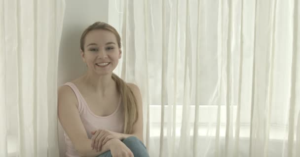 Vacker leende kvinna tittar på kameran hemma i vardagsrummet — Stockvideo