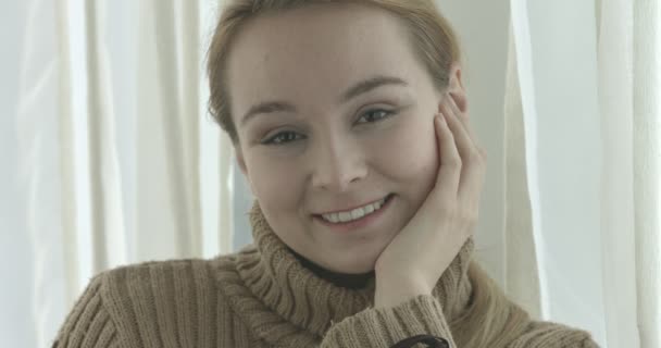 Mulher sorridente bonita olhando para a câmera em casa na sala de estar — Vídeo de Stock