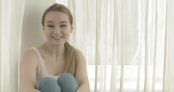 Hermosa mujer sonriente mirando a la cámara en casa en la sala de estar — Vídeos de Stock