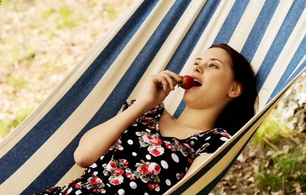 Vrouw die aardbeien eet in hangmat — Stockfoto