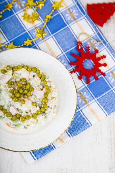 La ensalada Olivier sobre la mesa con las decoraciones navideñas. Navidad C — Foto de Stock