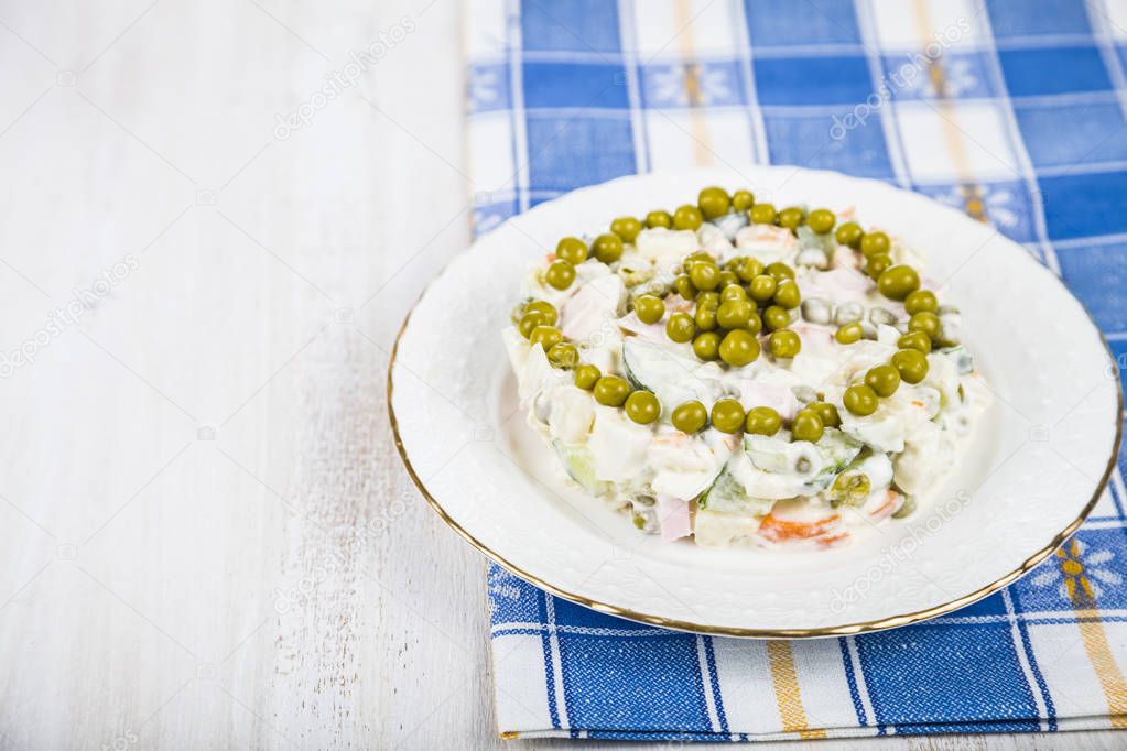 Delicious salad on a wooden table with a blue cloth. Salad Olivi