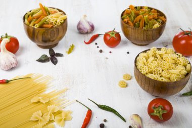 Pişmemiş makarna ve ahşap masa içinde baharatlar. Makarna ve malzemeler: chi