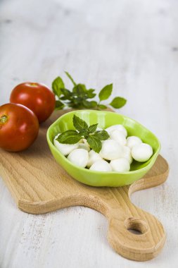 Mozzarella ahşap bir masa üzerinde yeşil bir tabak içinde. Mozzarella topları 