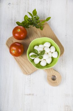 Mozzarella ahşap bir masa üzerinde yeşil bir tabak içinde. Mozzarella topları 