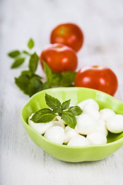 Mozzarella ahşap bir masa üzerinde yeşil bir tabak içinde. Mozzarella topları 
