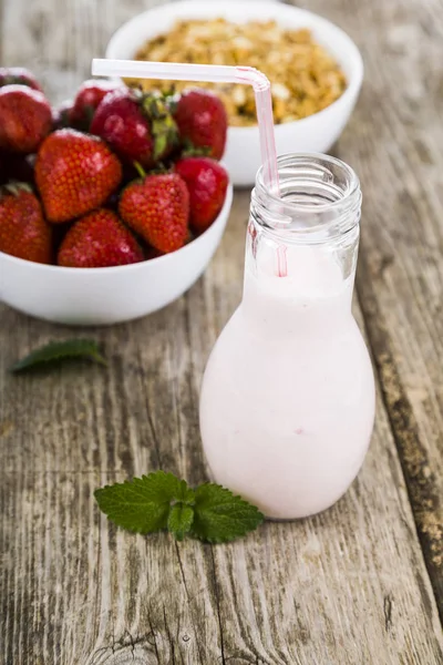 Smoothies e morango maduro em uma mesa de madeira. Bebida láctea com — Fotografia de Stock