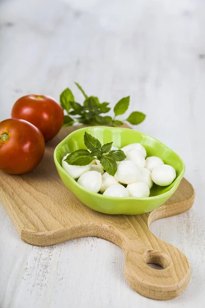 Mozzarella ahşap bir masa üzerinde yeşil bir tabak içinde. Mozzarella topları 