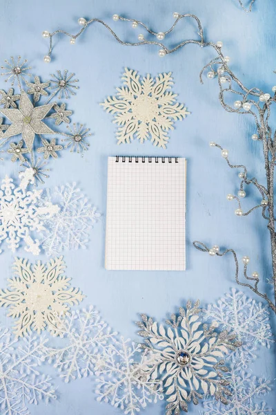 Silver decorative snowflakes and a notebook on a blue wooden bac — Stock Photo, Image