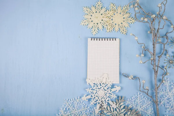 Silver decorative snowflakes and a notebook on a blue wooden bac — Stock Photo, Image