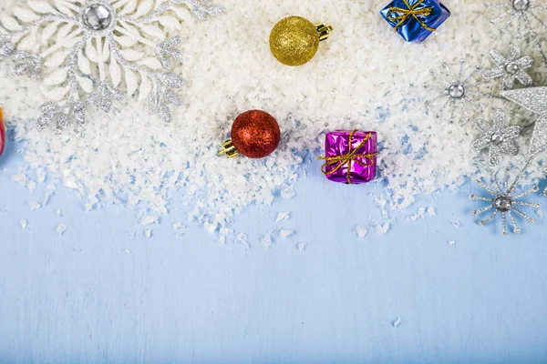 Silberne dekorative Schneeflocken und Schnee auf blauem Holzhintergrund — Stockfoto
