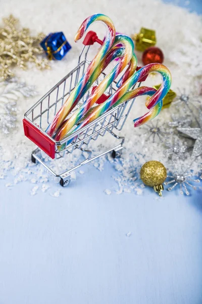 Shopping cart with Christmas candy in the snow. Concept of Chris