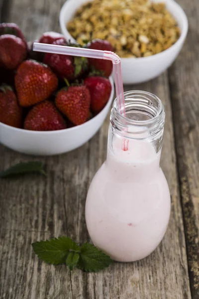 Frullati e fragola matura su un tavolo di legno. Bevanda al latte con — Foto Stock