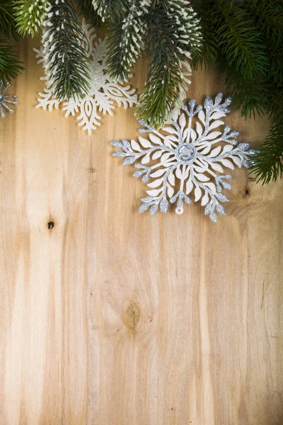 Srebrne płatki śniegu i gałęzie jodły na drewnianym stole. Boże Narodzenie — Zdjęcie stockowe
