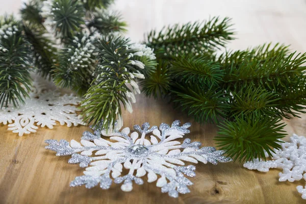 Silver snöflingor och fir grenar på ett träbord. Jul — Stockfoto