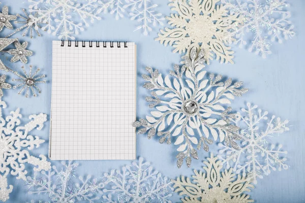 Silver decorative snowflakes and a notebook on a blue wooden bac — Stock Photo, Image