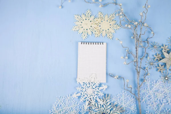 Copos de nieve decorativos de plata y un cuaderno en un bac de madera azul — Foto de Stock